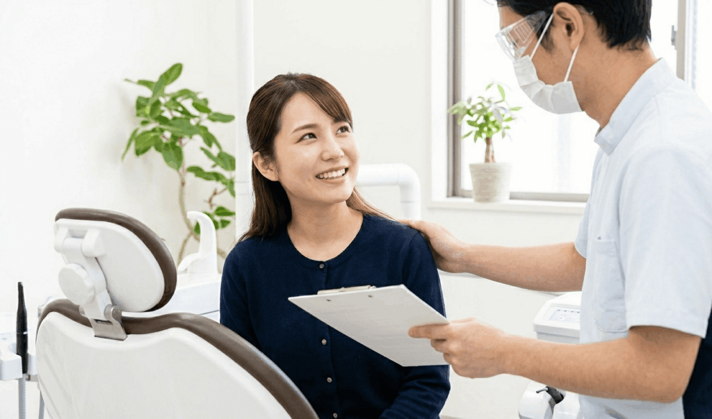 治療後に診療ユニットで晴れやかな笑顔を見せる日本人女性と歯科医の様子