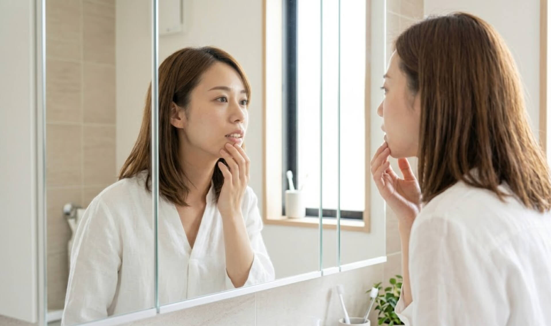鏡の反射を利用して、真剣な表情で口元のEラインを確認する女性の様子
