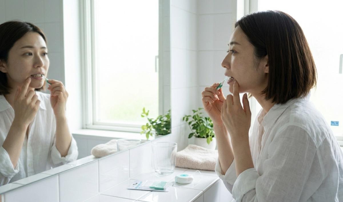 毎日のセルフケアで歯間ブラシを使う女性の様子