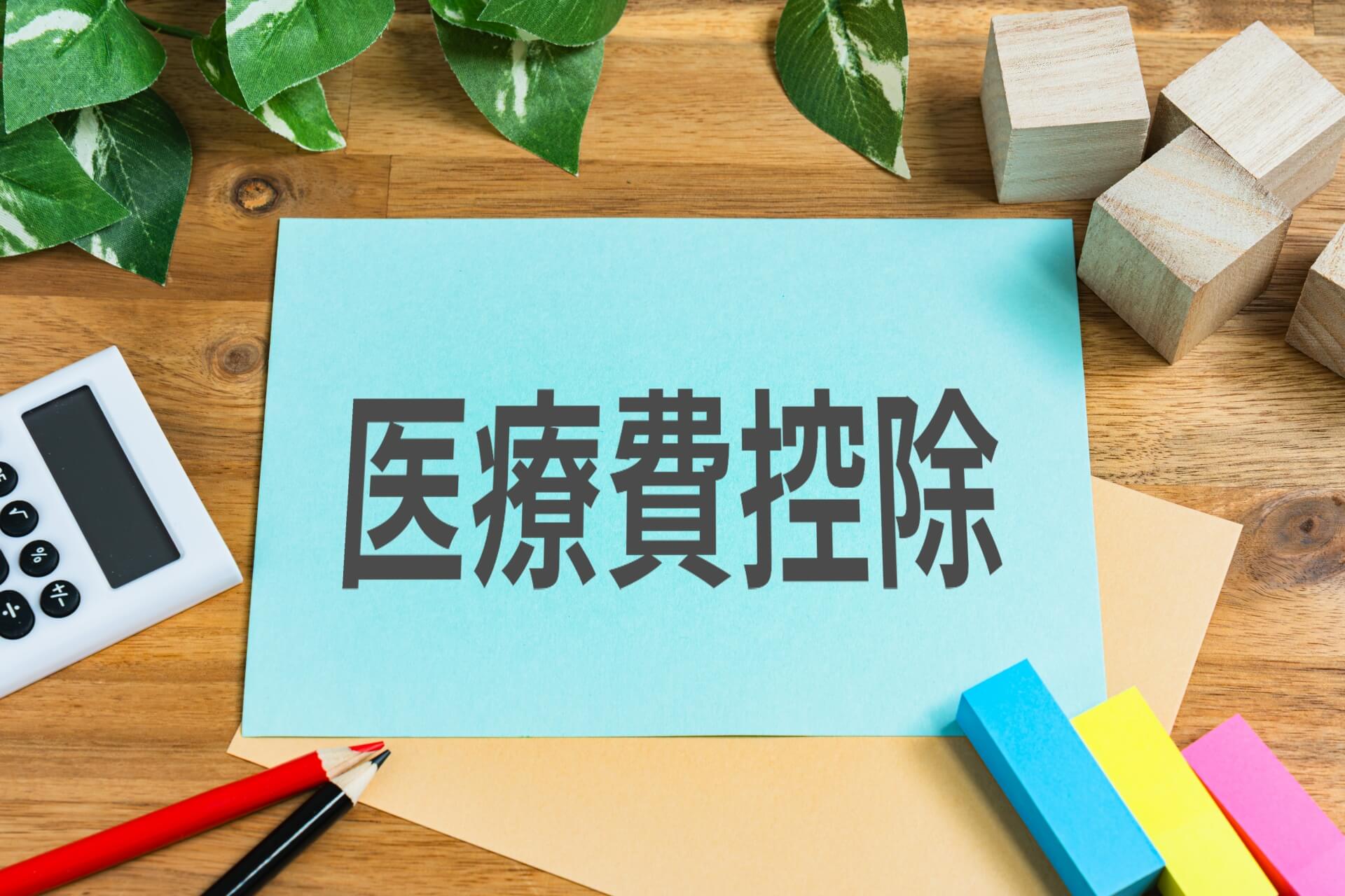 確定申告の仕組みを説明する、中央に「医療費控除」と書かれたカードがある卓上風景