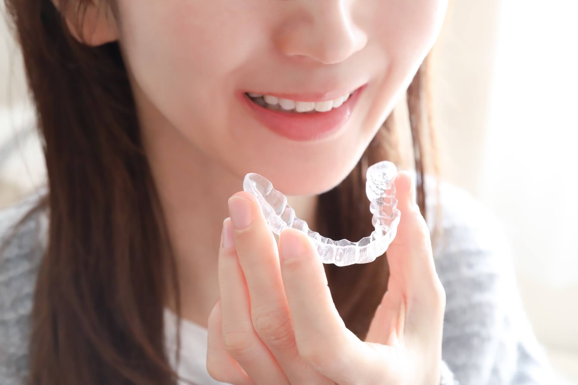 透明な矯正用マウスピースを確認する女性の様子