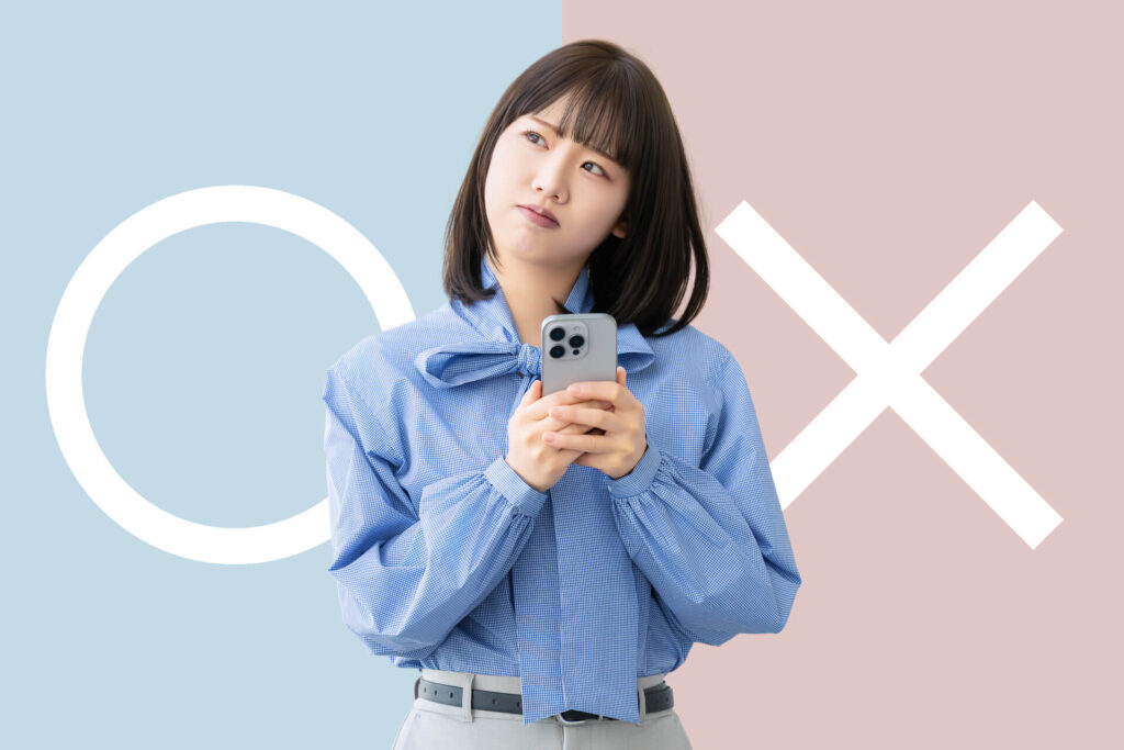 スマートフォンを手に持ち、保険適用か自費診療かで悩む表情を浮かべる日本人女性の様子