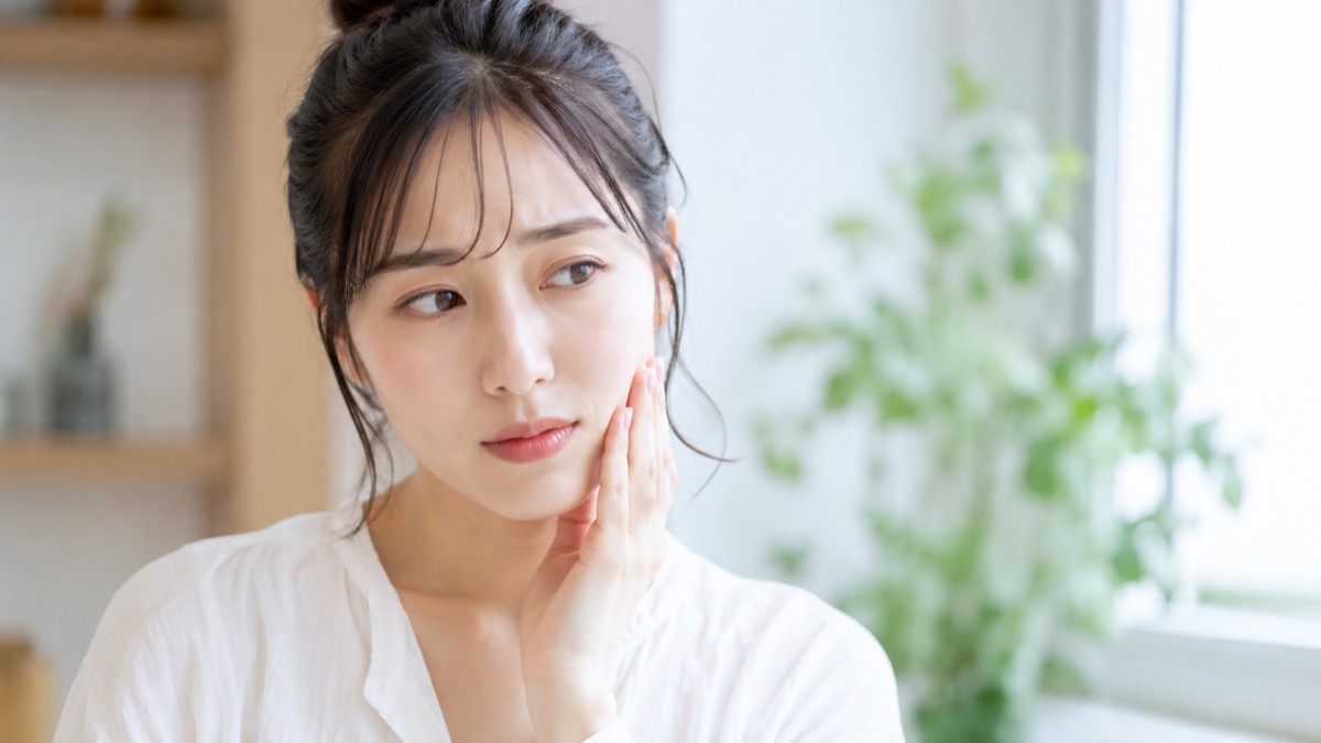 親知らずが気になり口元に手を当てる女性の様子